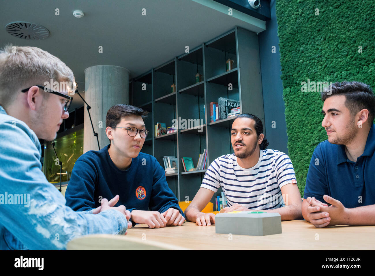 Un groupe de jeunes gens assis autour d'une table à discuter avec l'autre. Banque D'Images