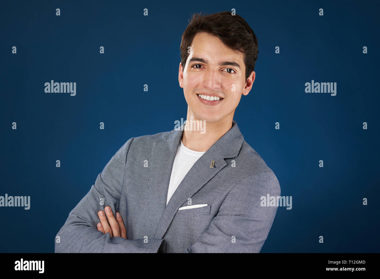 Portrait de jeune homme avec bras croisés isolé sur fond bleu Banque D'Images