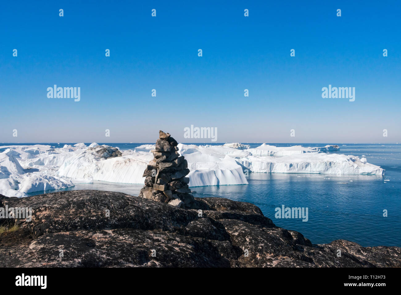 Cairn (tas de pierres) avec vue sur les icebergs de Sermermiut, Ilulissat, Groenland. Banque D'Images