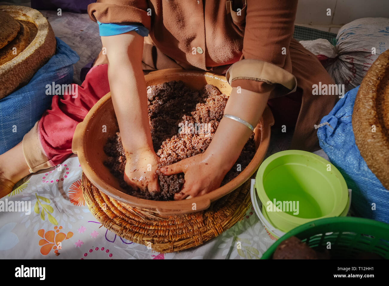 Femme marocaine locale de pétrissage à la main grasse d'argan coller afin d'extraire l'huile d'Argan. Essaouira, Maroc. Banque D'Images