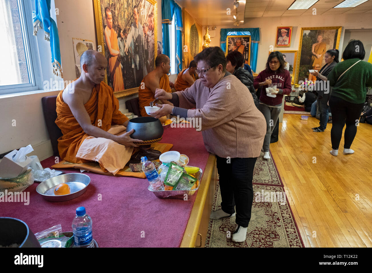Une femme à un temple bouddhiste thaï sert de la nourriture à l'un des moines, un rituel effectué après la prière des services. Dans Elmhurst, Queens, New York City Banque D'Images