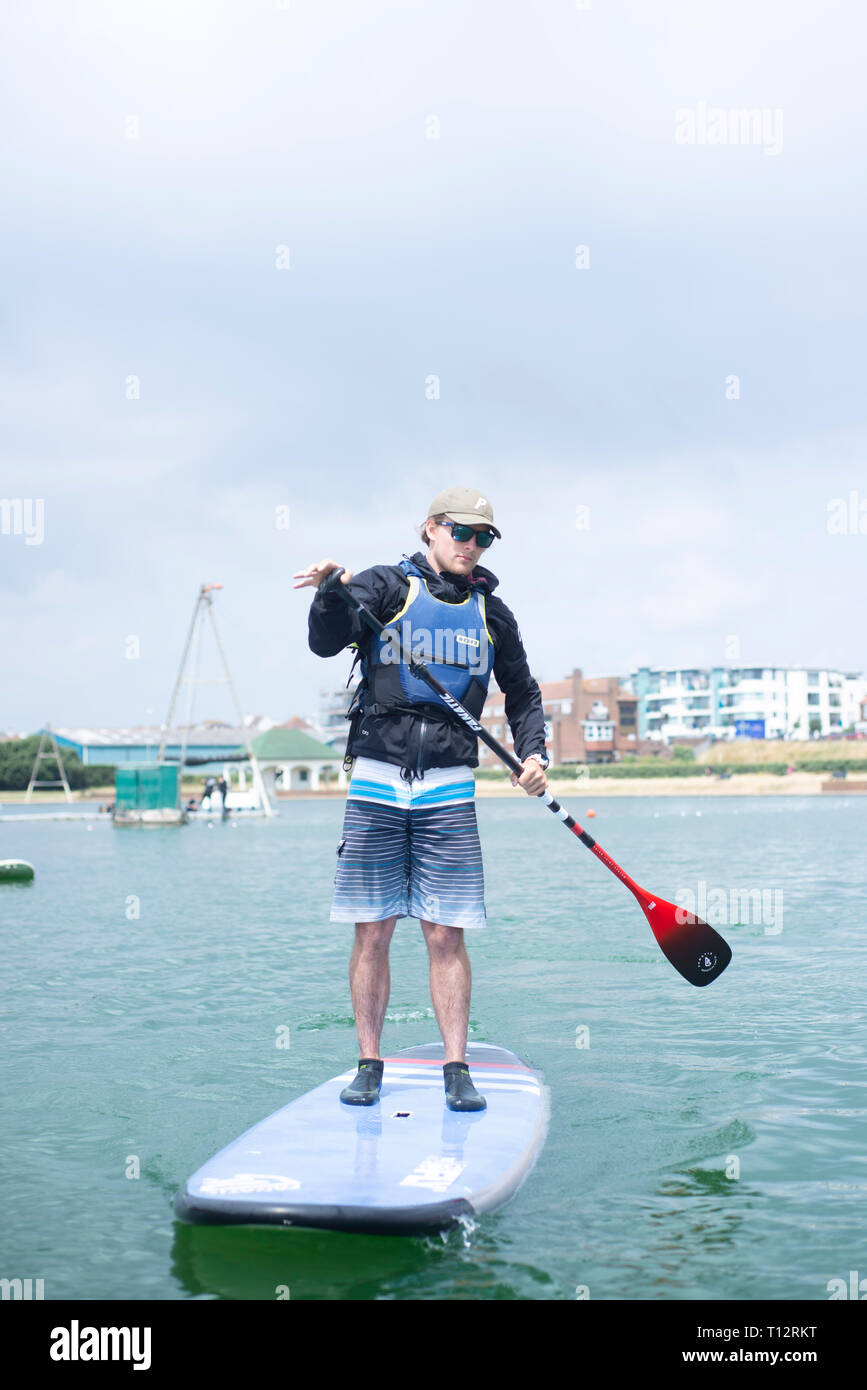 Un mâle en stand up paddle boarder à Hove Lagoon Banque D'Images