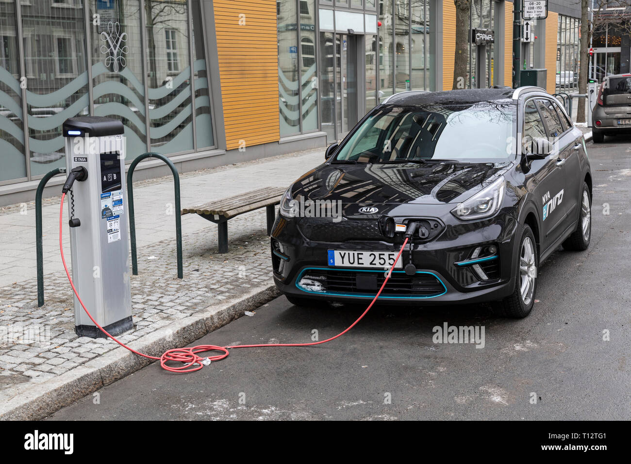 Une Kia Niro Plug In Hybrid car attaché à une station de charge électrique par le côté d'une route dans la ville de Trondheim en Norvège. Banque D'Images