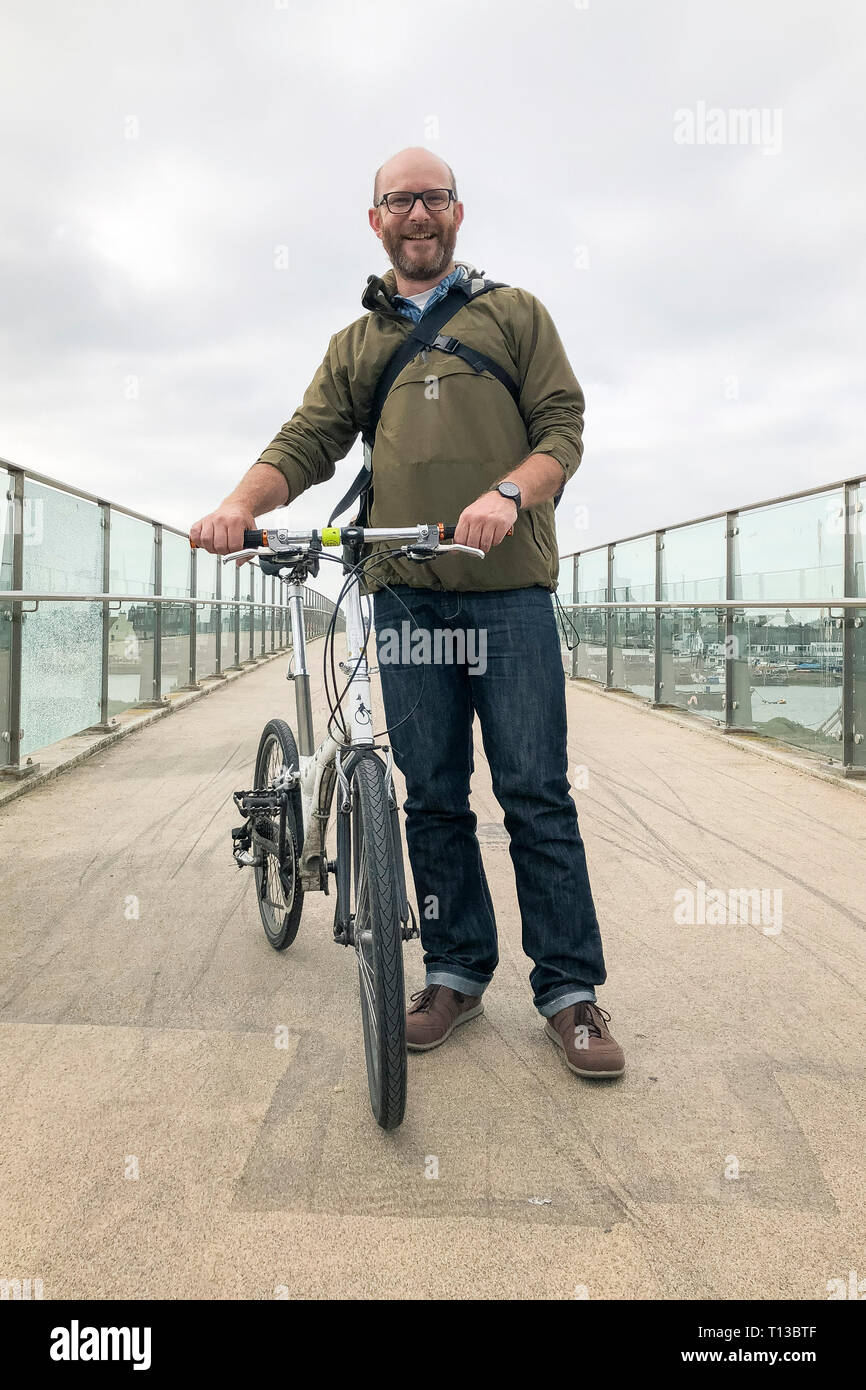 Un homme blanc se dresse sur l'Adur Shoreham Ferry Bridge avec un vélo pliant Banque D'Images