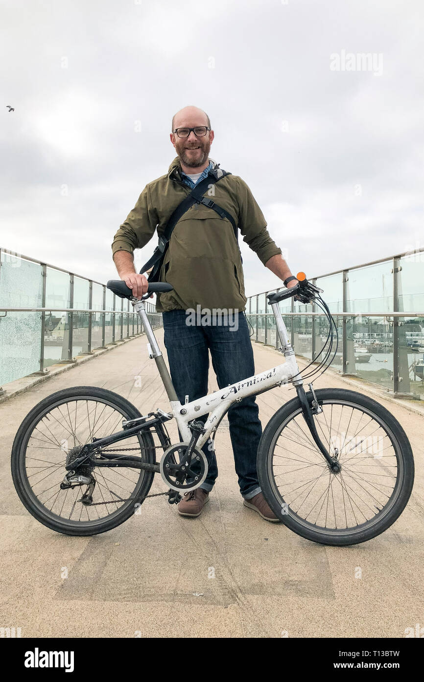 Un homme blanc se dresse sur l'Adur Shoreham Ferry Bridge avec un vélo pliant Banque D'Images