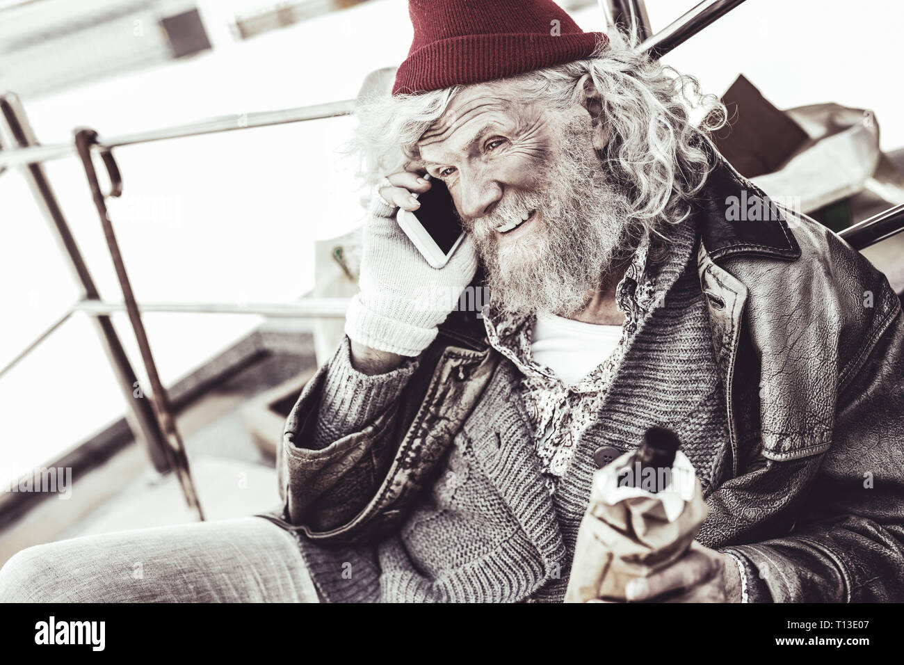 Homme non hygiéniques avec une bouteille dans la main appelant avec smartphone. Banque D'Images