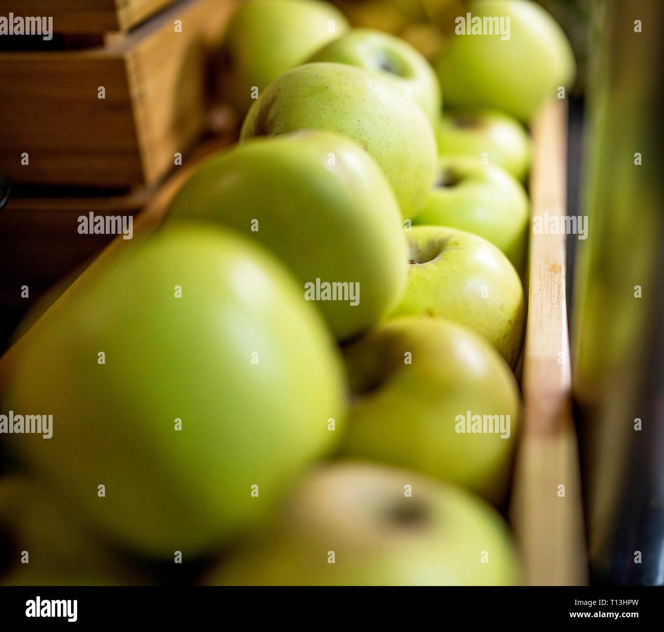 Close up de mûres et de pommes Golden Delicious dans une caisse en bois sur un étal de marché. Banque D'Images