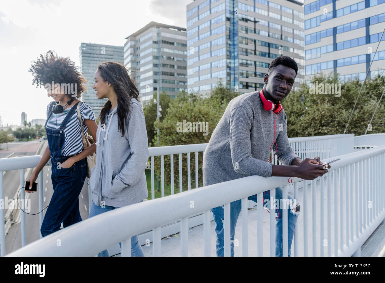 Jeune homme avec un casque debout sur le pont, à l'aide de smartphone, jeunes en marche Banque D'Images