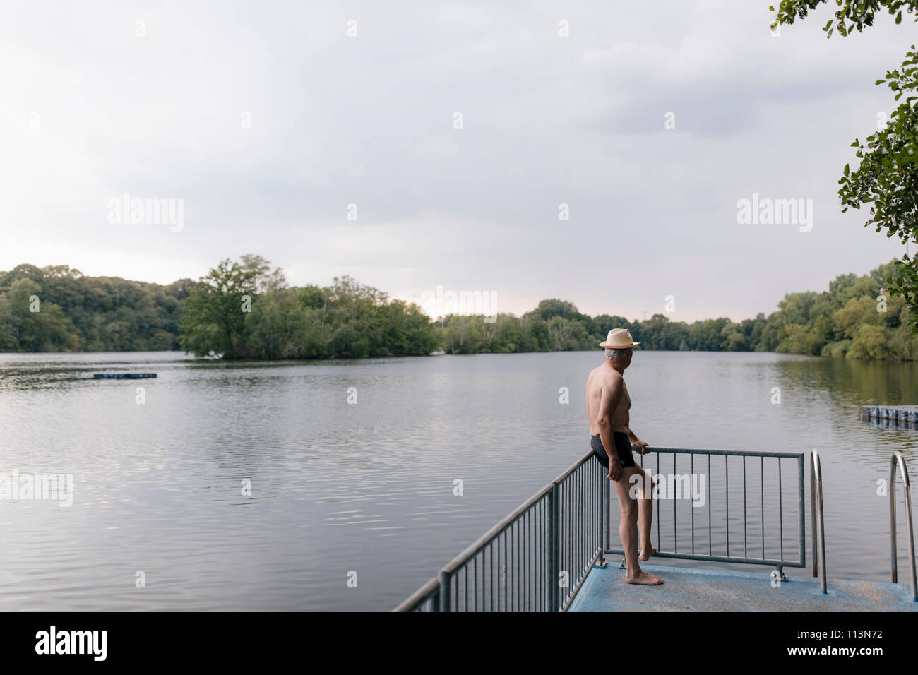 Senior man wearing straw hat standing at a lake Banque D'Images