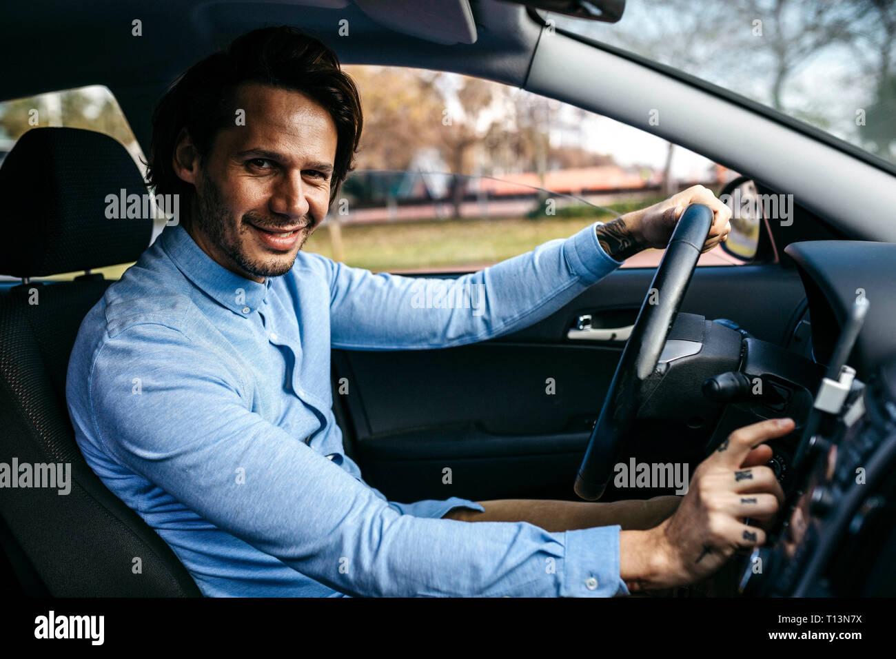 Portrait of smiling businessman driving car l'utilisation de téléphone cellulaire comme système de navigation Banque D'Images