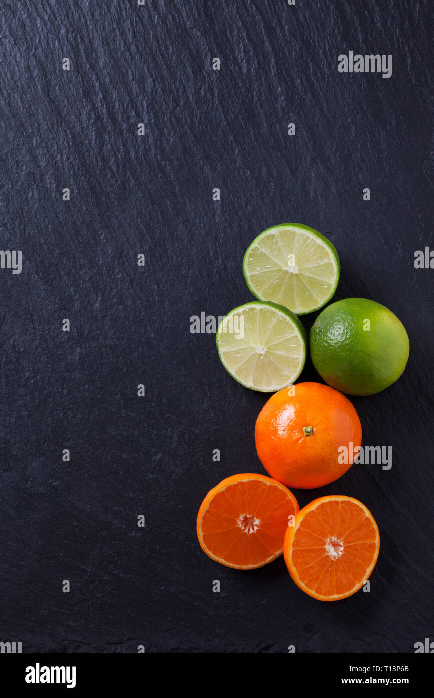 Limes et de tangerines sur dalle d'ardoise noire Banque D'Images