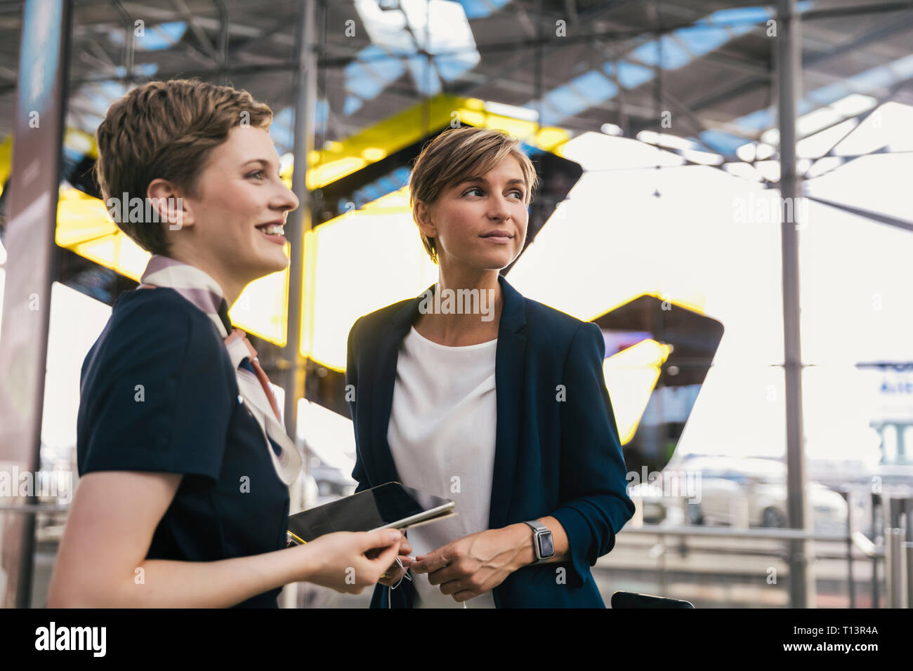 Smiling airline employé avec tablet et femme d'affaires à l'aéroport. Banque D'Images
