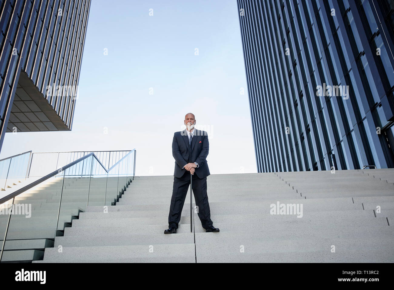 Elegant businessman avec canne, debout dans les escaliers dans la ville Banque D'Images