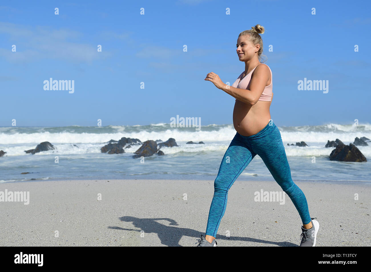 Smiling pregnant woman jogging sur la plage Banque D'Images