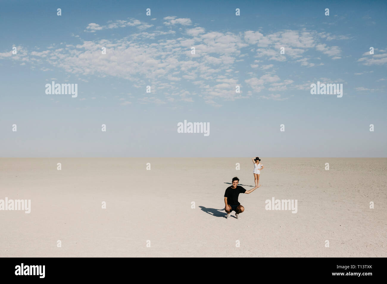 Homme à genoux dans le désert, avec femme semblant à l'équilibre sur sa main Banque D'Images