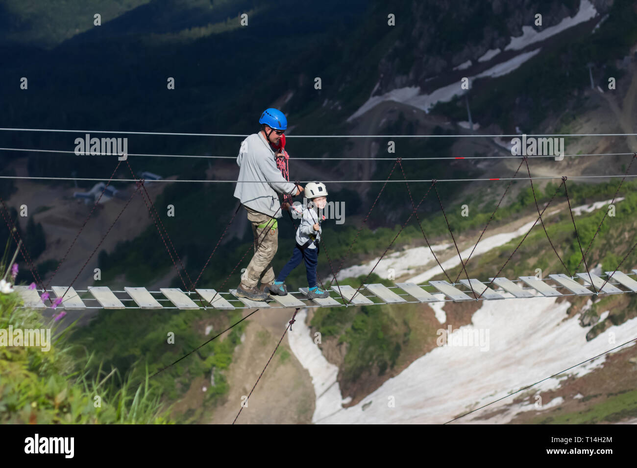 Adulte et enfant sur un pont de corde dans les montagnes, nature extrême de repos Banque D'Images