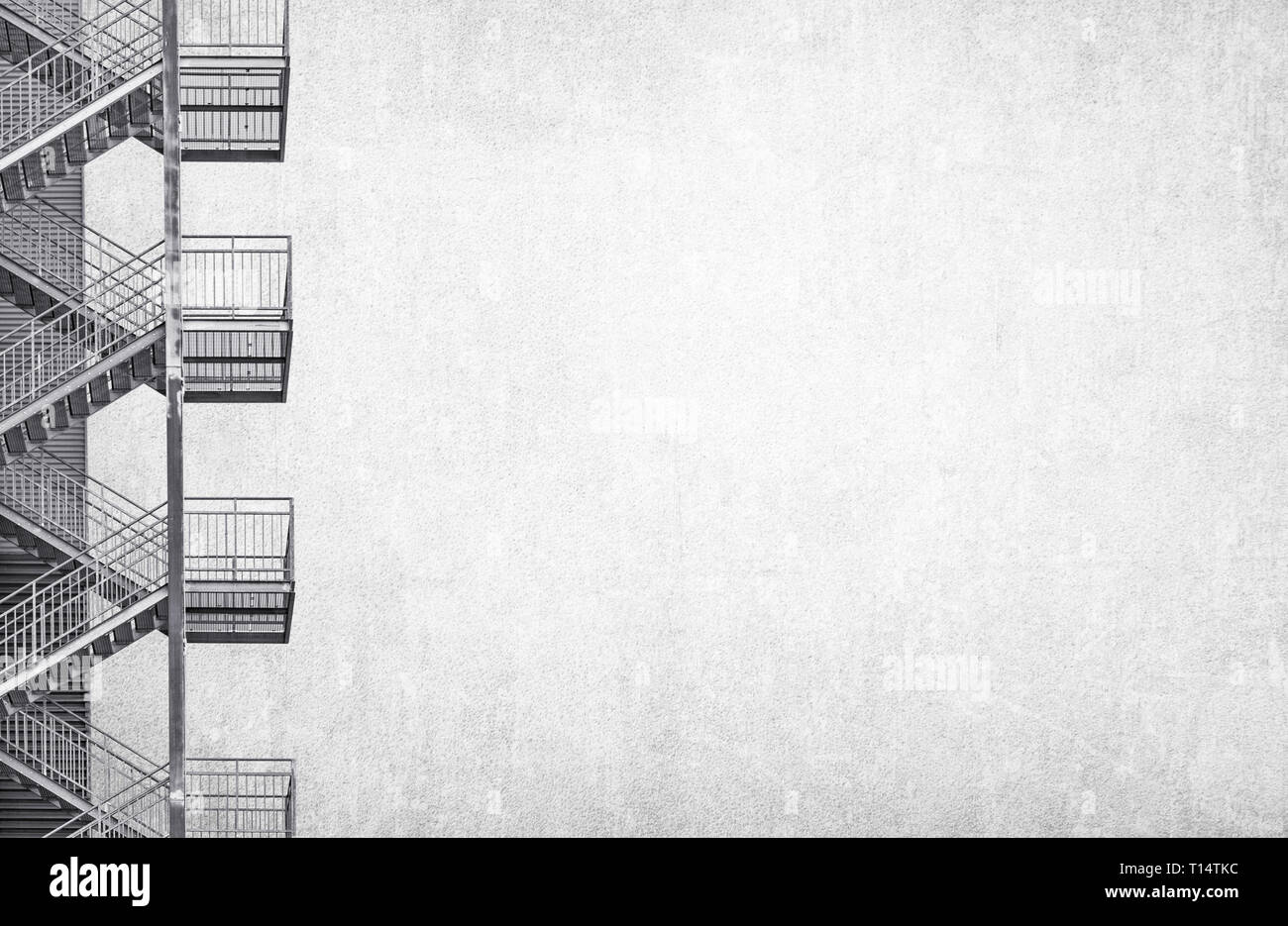 Escalier industriel métallique isolé sur fond gris mur en détresse. Photo noir et blanc avec beaucoup d'espace sur le droit de copie Banque D'Images