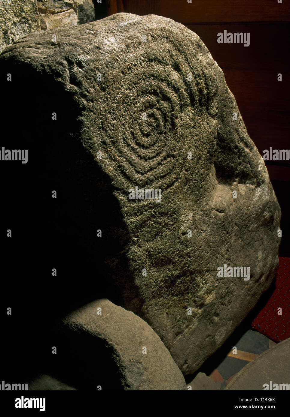 Une pierre sculptée en spirale néolithique (sens horaire, 7 boucles avec 2 mini-cupmarks), conservé dans l'église St Pierre, Llanbedr, Gwynedd, Pays de Galles, Royaume-Uni. Banque D'Images