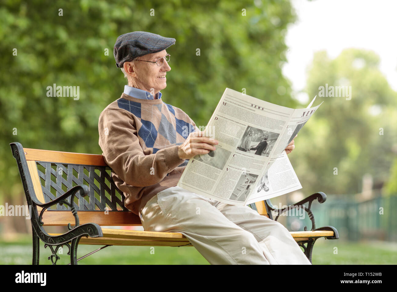 Senior man reading a newspaper dans le parc sur un banc Banque D'Images