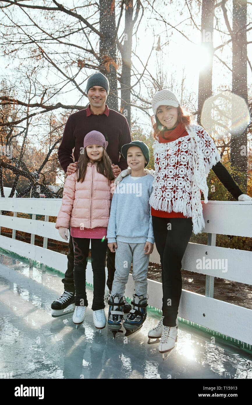 Famille leaning on railing à la patinoire Banque D'Images