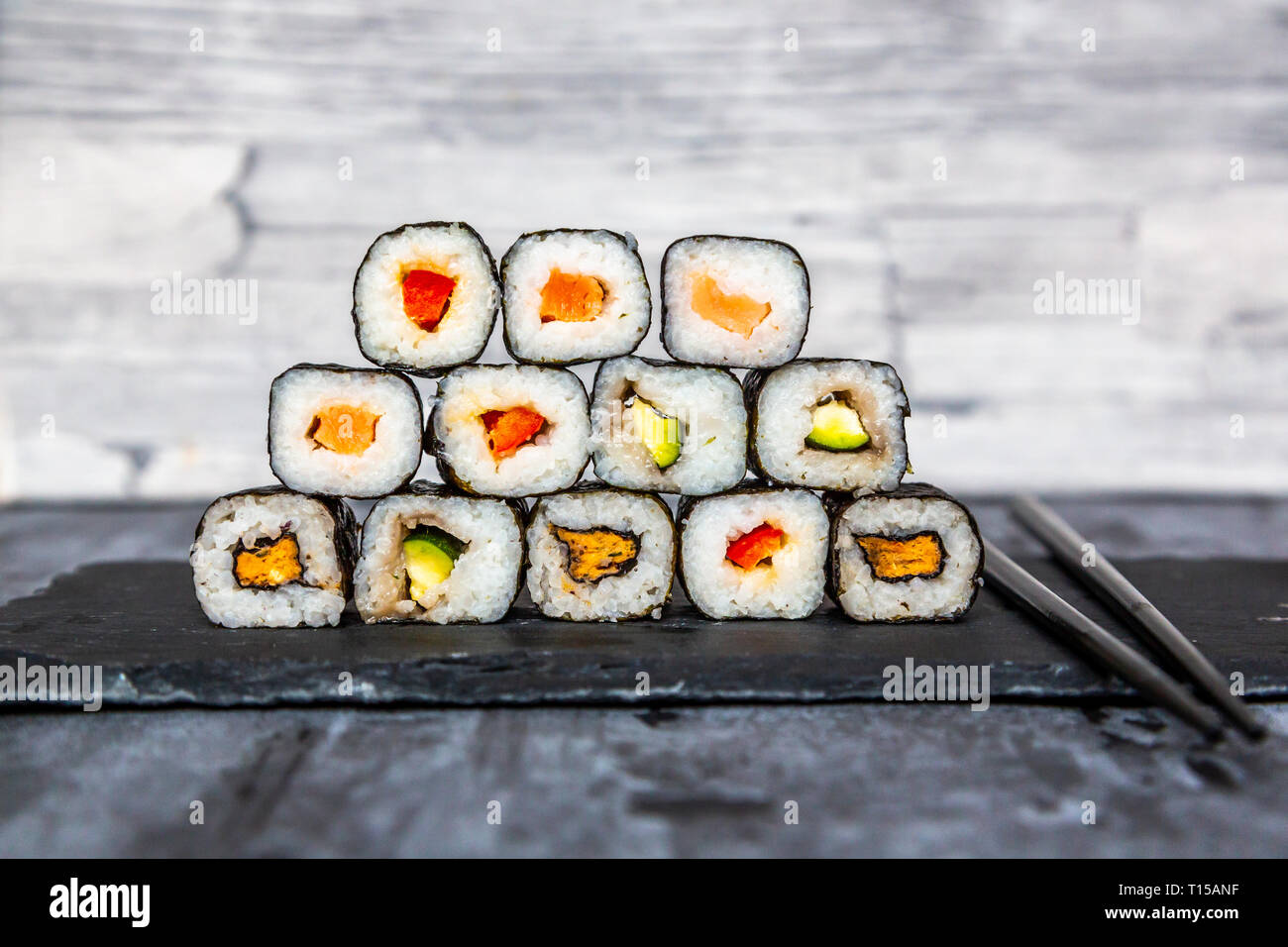 Sushi empilées sur dalle d'ardoise, baguettes Banque D'Images