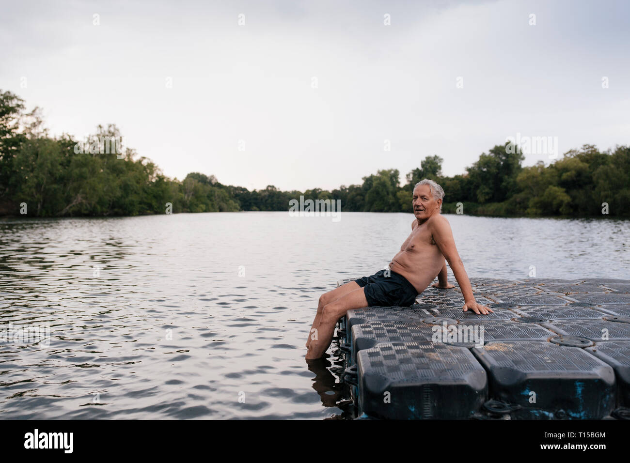 Senior man sitting on raft dans un lac Banque D'Images