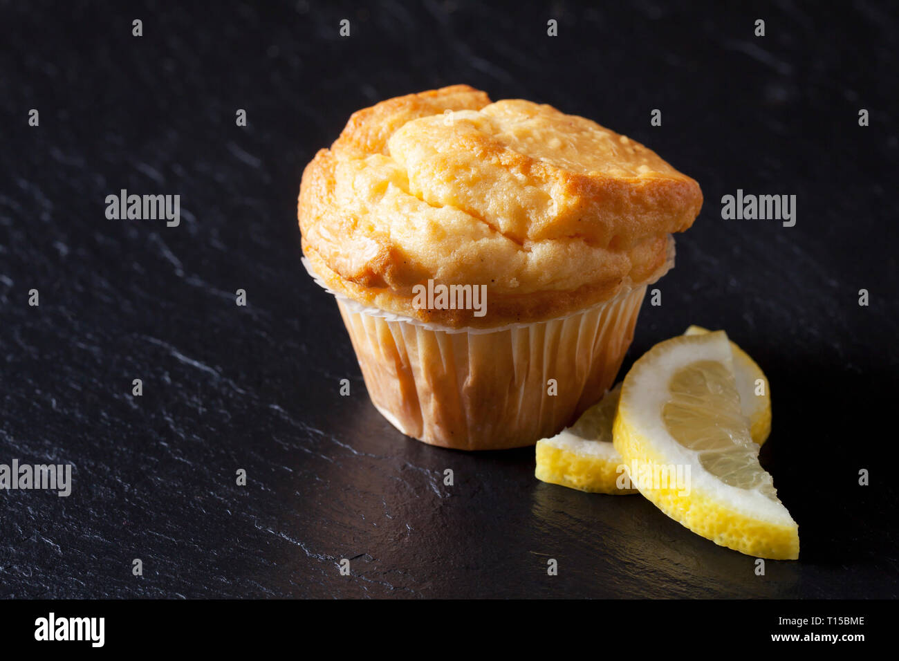 Muffin citron frais sur l'ardoise noire avec les tranches de citron Banque D'Images