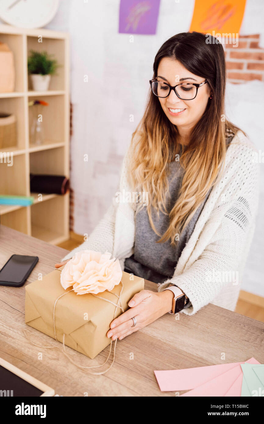 Jeune femme montrant un cadeau enveloppé dans son studio Banque D'Images