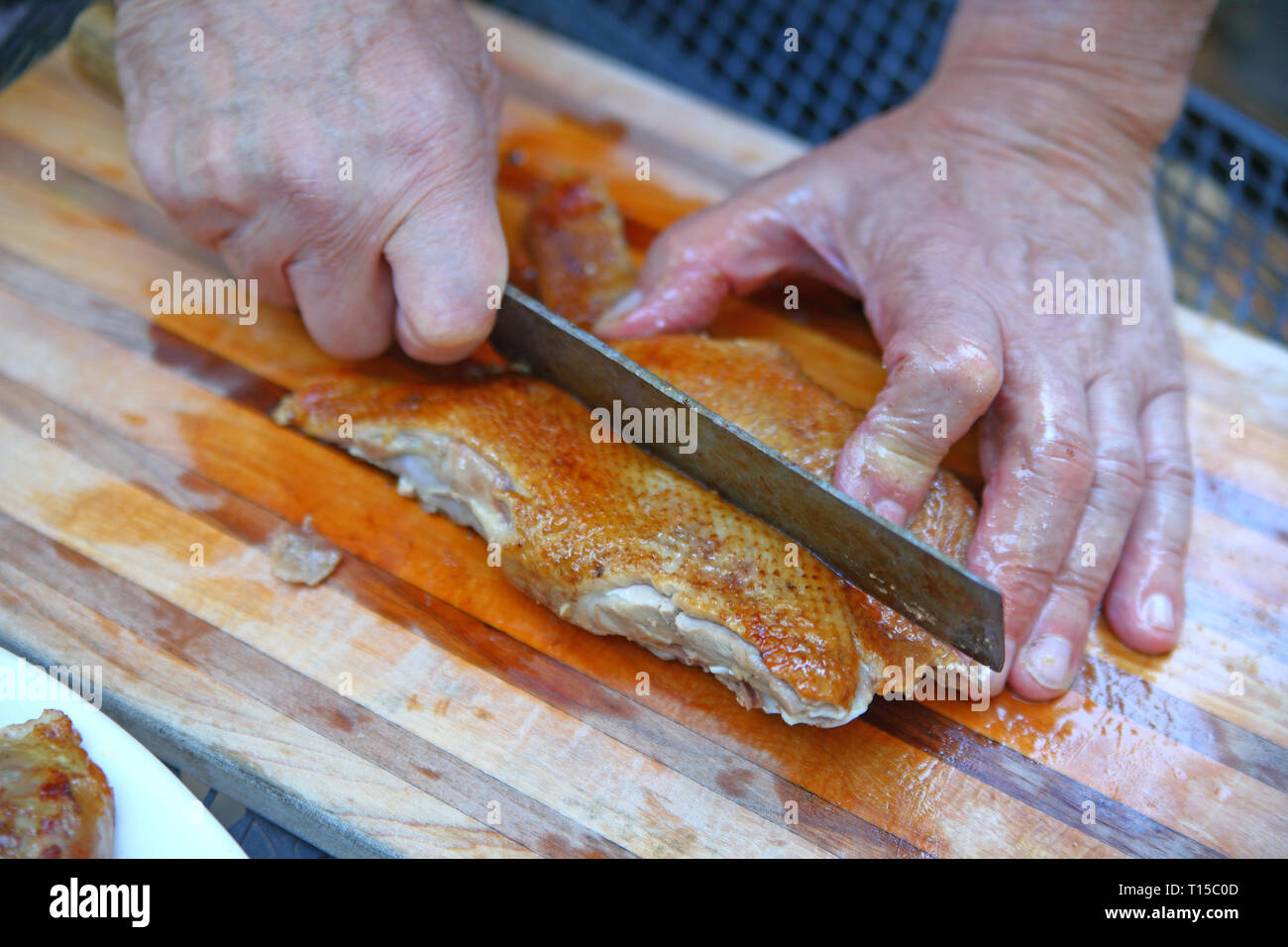 Un homme découpe un rôti de poitrine de canard libre Banque D'Images