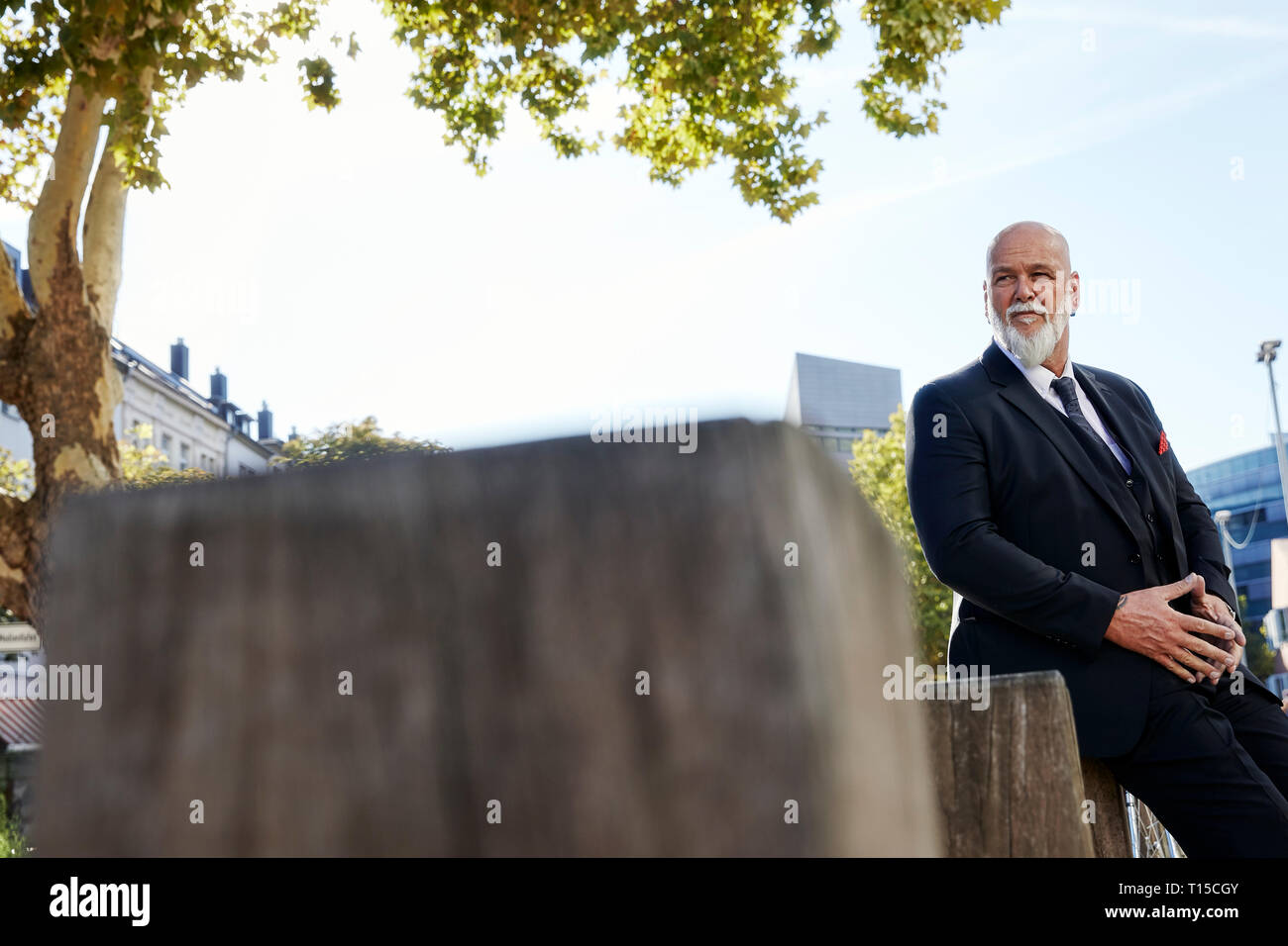 Elegant businessman leaning on un mur dans la ville Banque D'Images