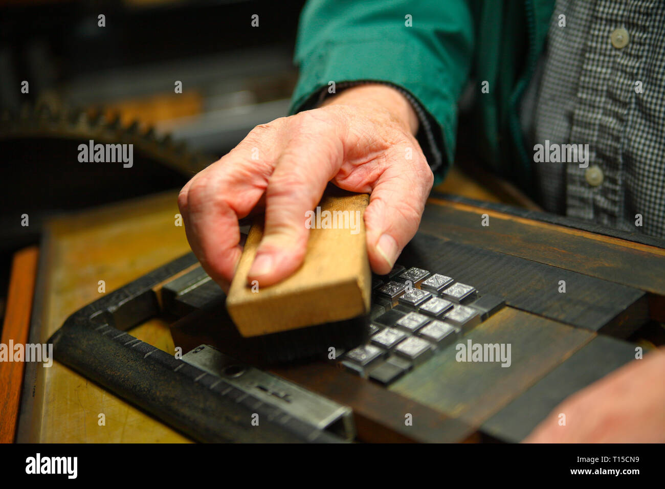 Un homme nettoie un alphabet de type métal avec un pinceau Banque D'Images