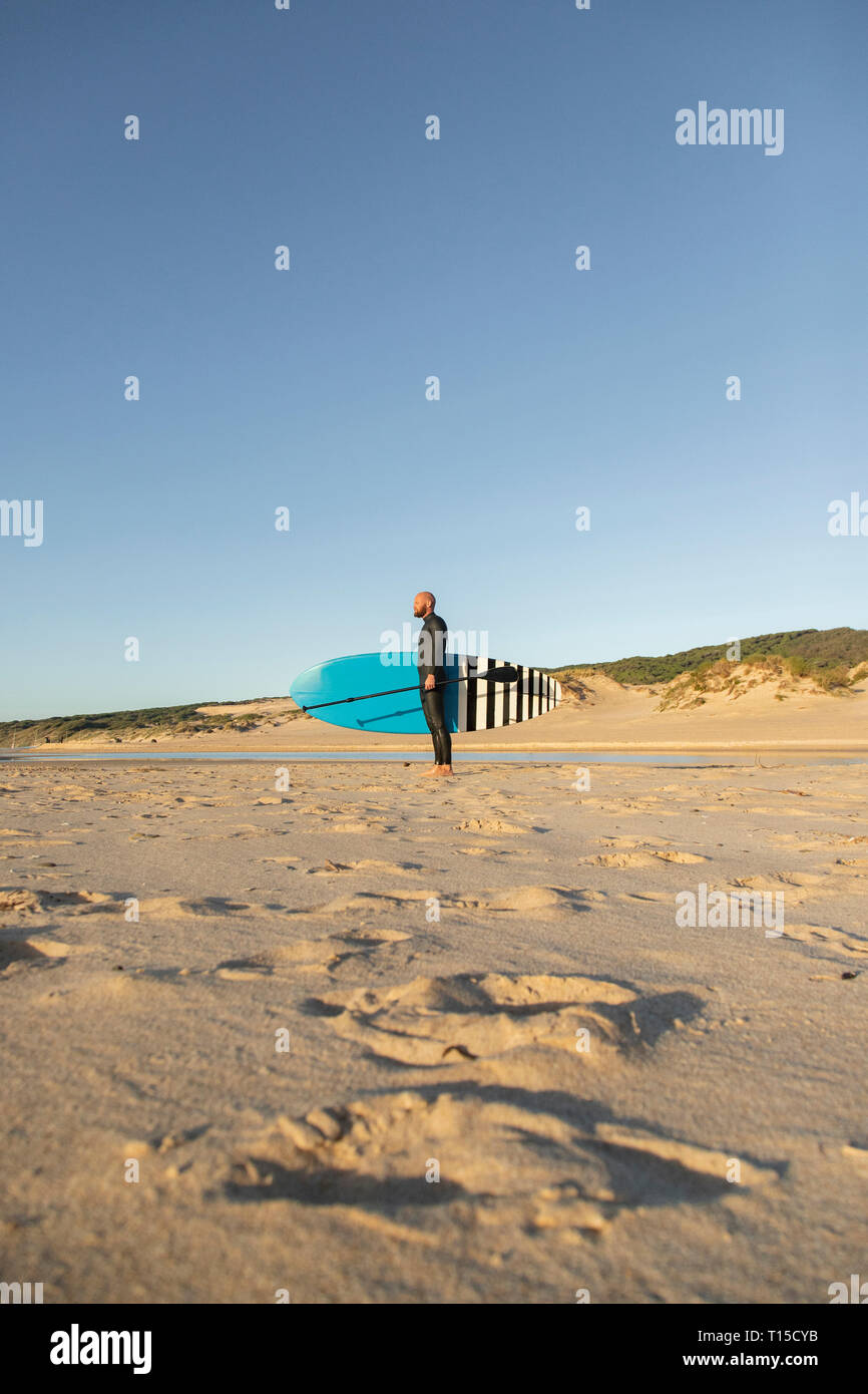 Espagne, Andalousie, Tarifa, l'homme avec stand up paddle board sur la plage Banque D'Images