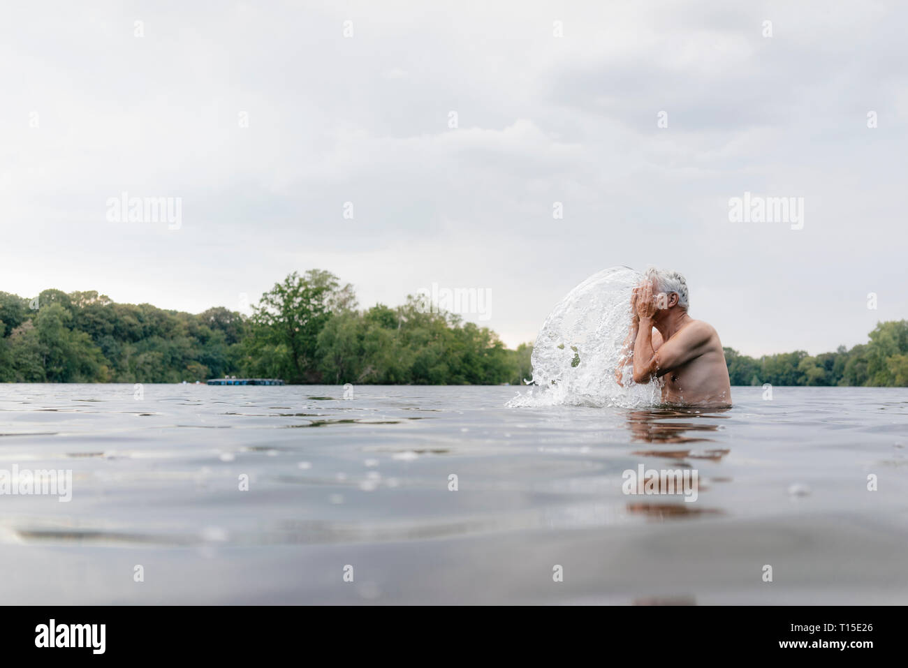 Man dans un lac aux projections d'eau sur son visage Banque D'Images