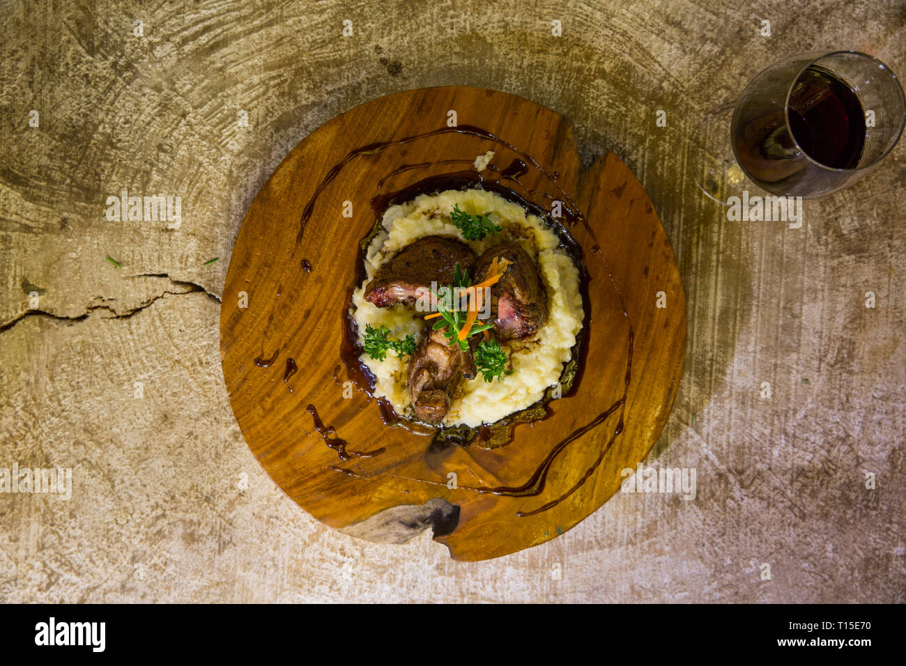 Garnie plat sur une assiette en bois à côté de verre de vin rouge Banque D'Images