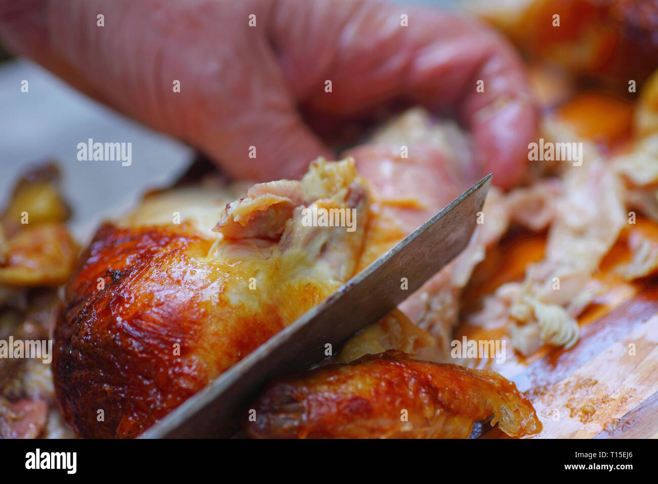 L'homme saisit le poulet, à l'aide d'un couteau de cuisine pour couper des morceaux Banque D'Images