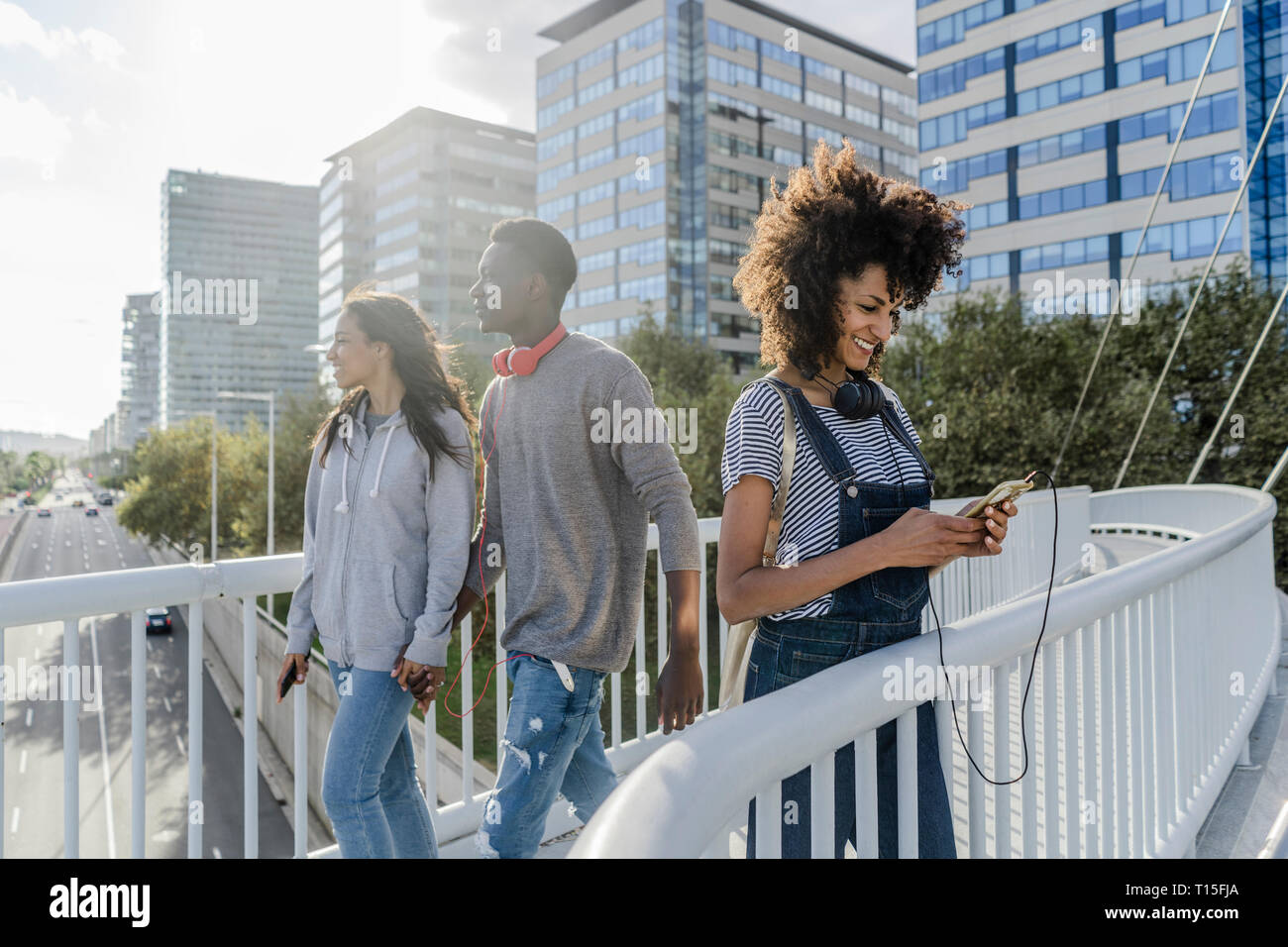 Jeune femme avec un casque debout sur le pont, à l'aide de smartphone, jeunes en marche Banque D'Images