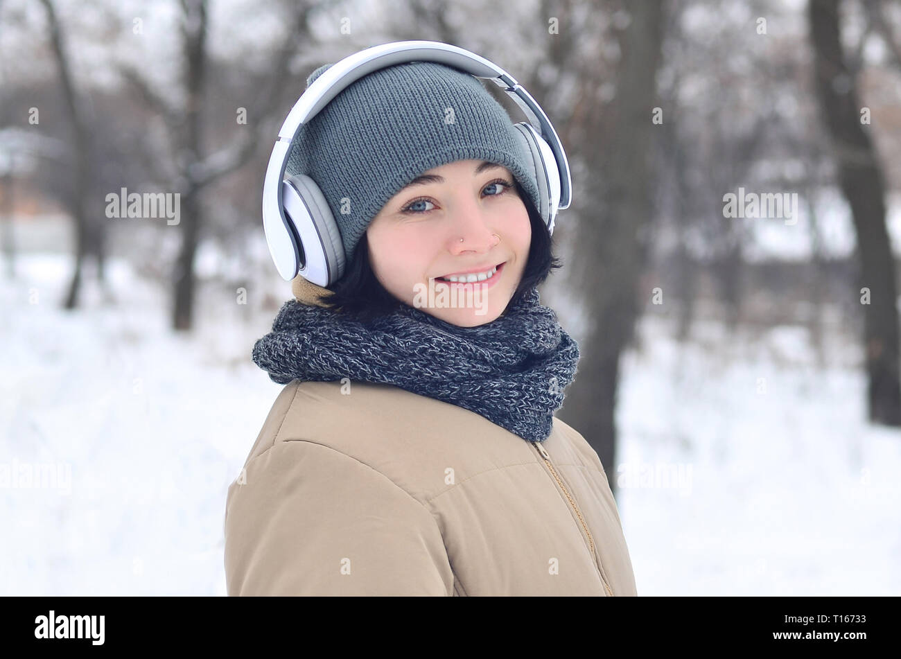 Jolie jeune fille porter des cache-oreilles d'hiver chaud et écharpe. Fun  brunette modèle féminin à l'extérieur avec un casque par temps froid.  Modèle Smiling happy pos Photo Stock - Alamy