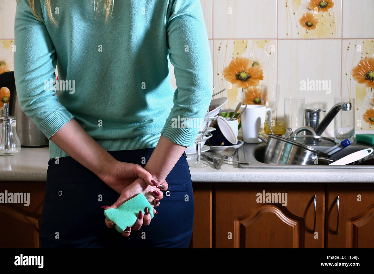 Fragment d'un corps de femme au comptoir de la cuisine, rempli de beaucoup de plats sales. La fille est fatigué de faire face à l'obligation quotidienne de lave-d Banque D'Images