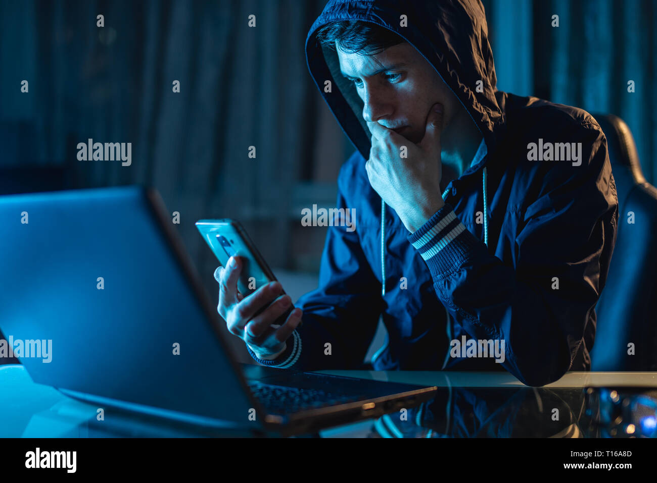Hacker dans le capot de tenir le téléphone dans ses mains essayant de voler des bases de données Access avec des mots de passe. Le concept de sécurité cybernétique Banque D'Images