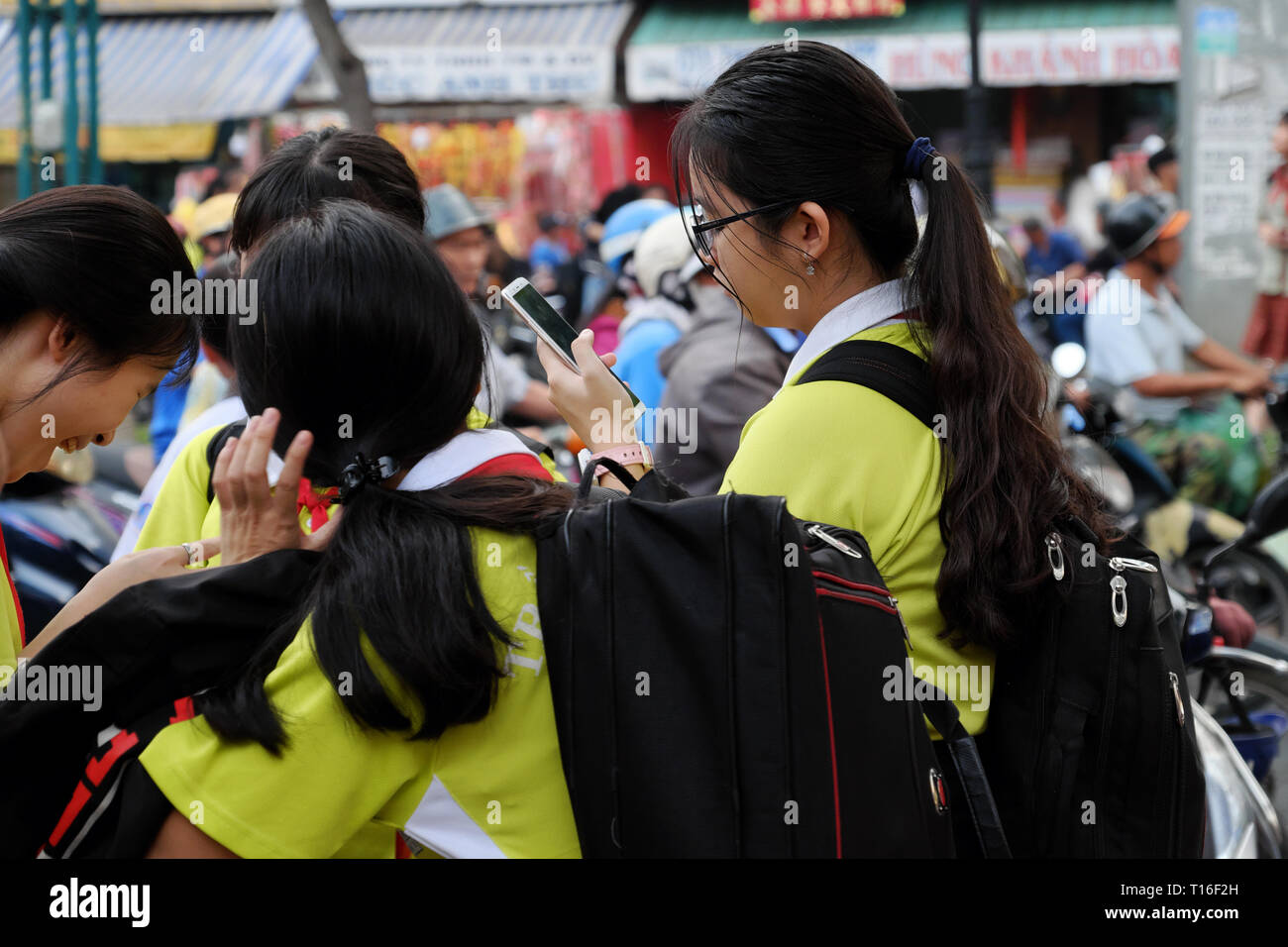 School girl stand avec i phone dans la main, l'accent sur smartphone après l'école, soirée close up tournage d'élève en t shirt uniforme, Vietnam Banque D'Images