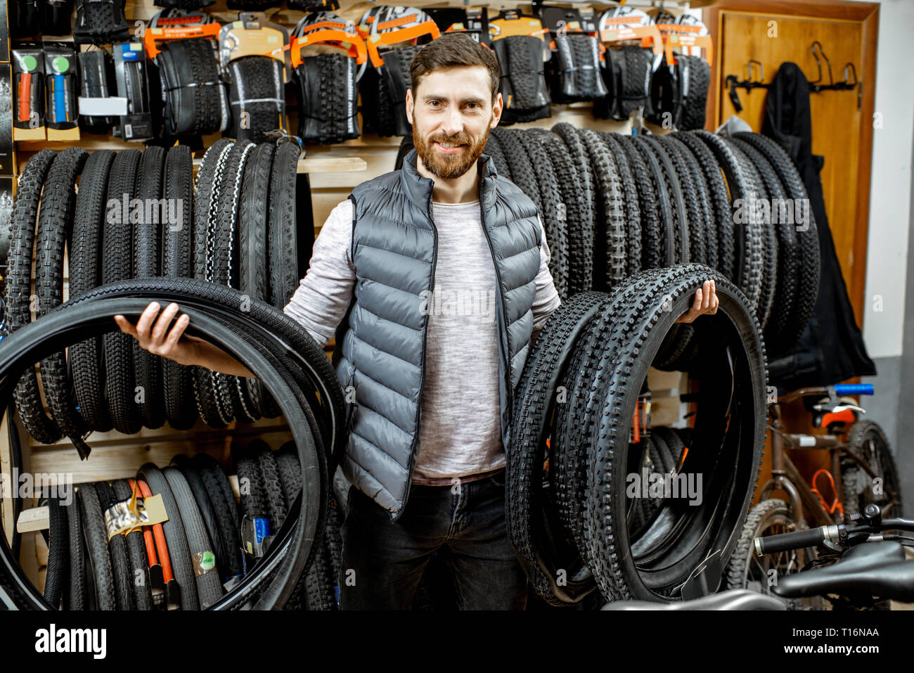 Portrait of a handsome vendeur ou propriétaire de boutique debout avec des pneus de bicyclettes dans le magasin de sport Banque D'Images
