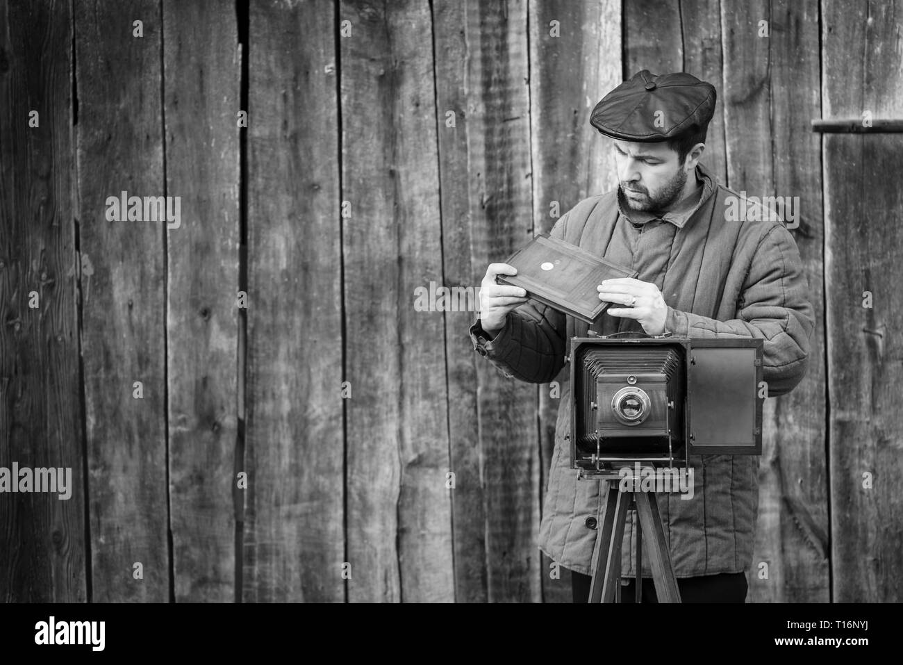 Photographe se prépare pour le tournage et l'insère dans le support film grand format rétro. Concept - Photographie des années 1930 aux années 1950, l'effet monochrome Banque D'Images