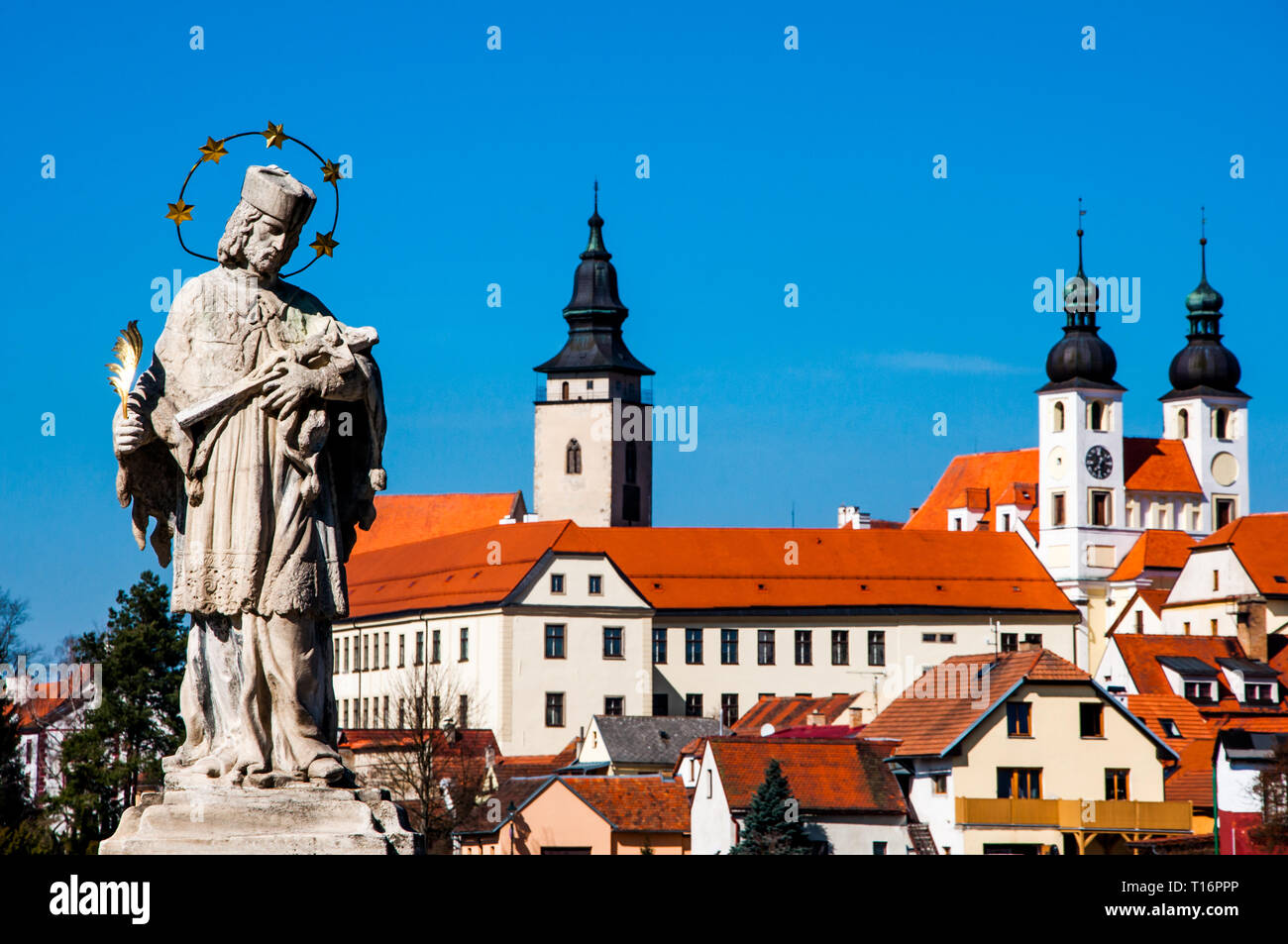 La Statue baroque de saint Jean Népomucène et Telc chateau avec église du saint Nom de Jésus en arrière-plan, Telc, région de Vysocina, République tchèque. Banque D'Images