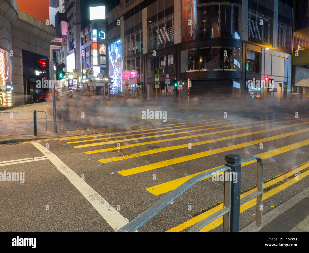 L'obturation lente avec les piétons qui traversent la rue à Queen's Road Central Hong Kong. Banque D'Images