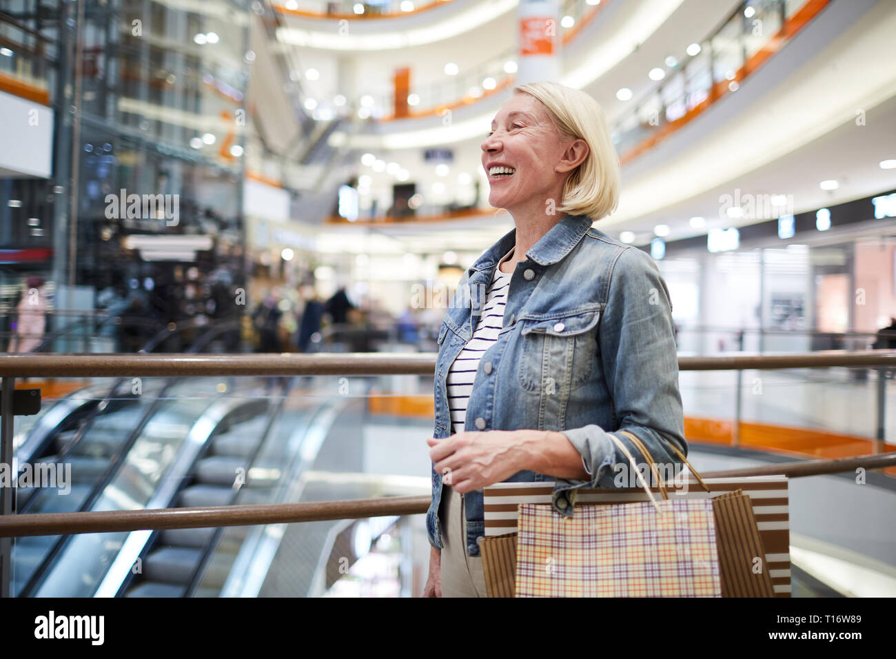 Femme mature positive faisant le tour des magasins dans mall Banque D'Images