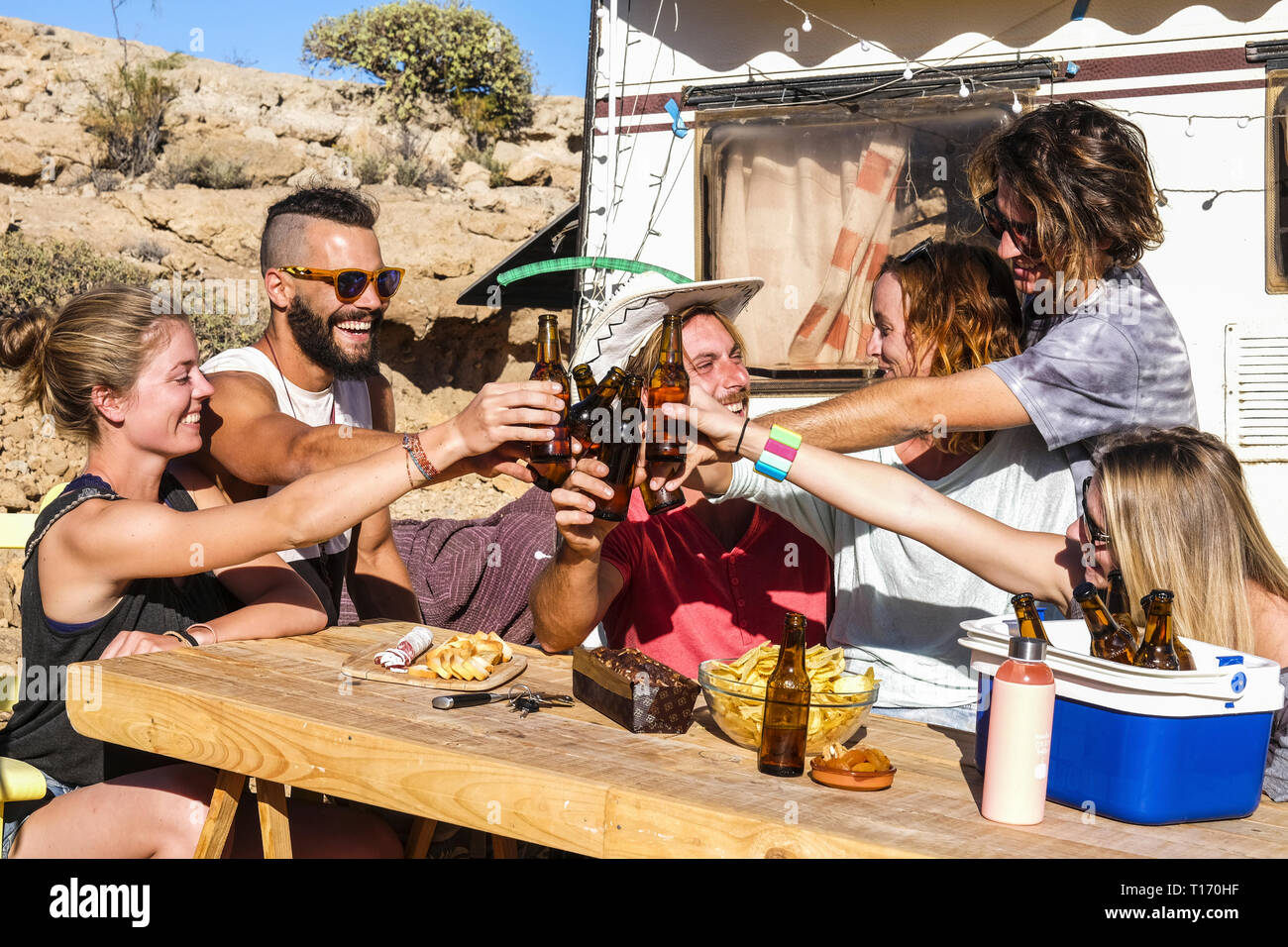 D'autres jeunes groupes d'amis people toasting et les bouteilles de bière de trinquer tous ensemble s'amuser dans l'amitié en milieu rural camping emplacement pour vacat Banque D'Images