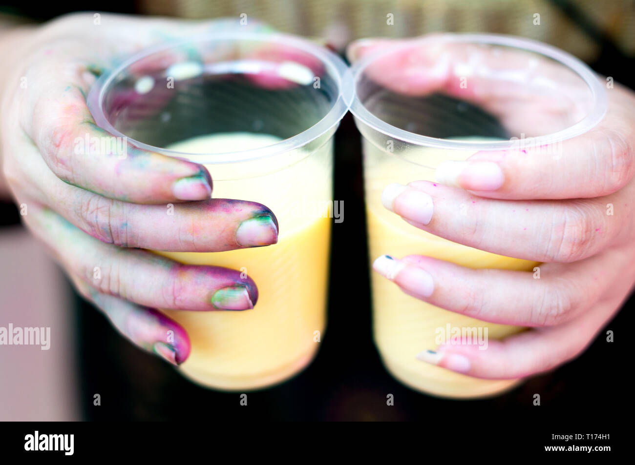 Colorful hands holding tasses jetables de thandai sur holi festival hindou Banque D'Images