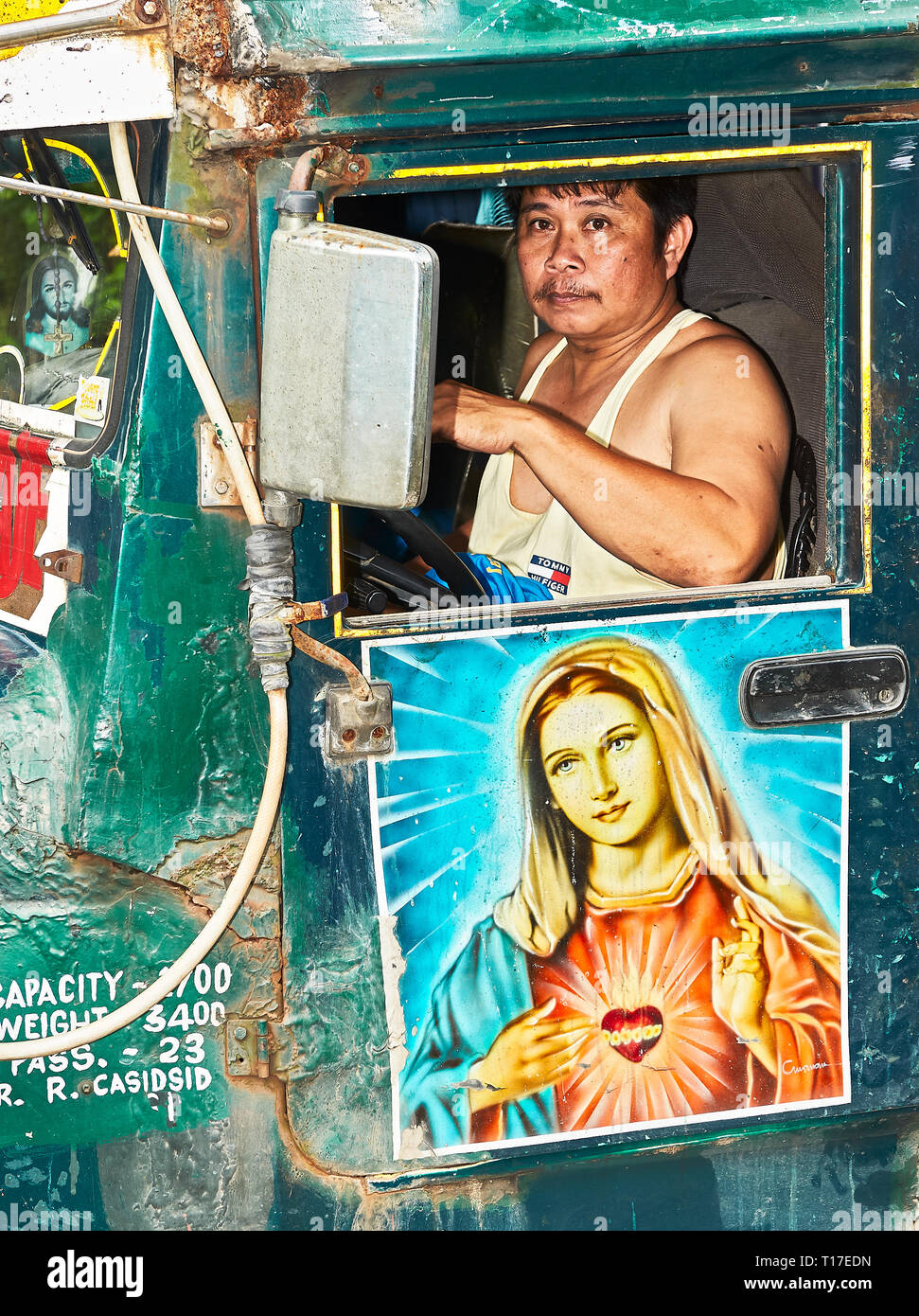 Ibajay, Aklan, Philippines : Le pilote d'un vieux Jeepney, décoré avec une peinture de la Vierge Marie, se joindre au Festival Ati-Atihan Banque D'Images