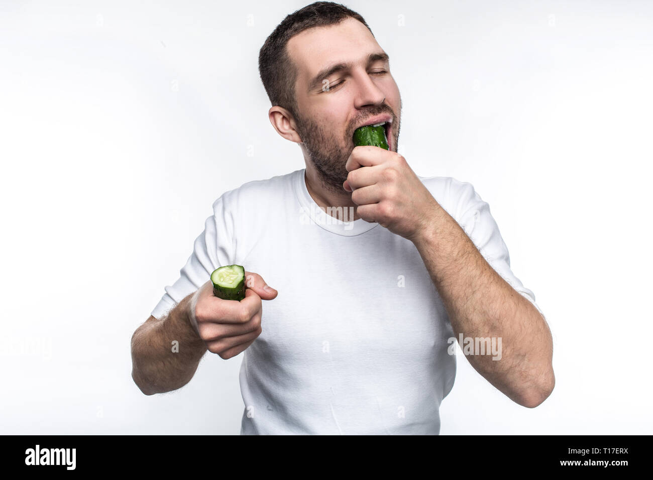 Ce mec aime manger bio et naturelle des fruits et légumes. Sur cette photo il a deux pièces d'un long concombre. Il est également l'un des piqueurs ce Banque D'Images