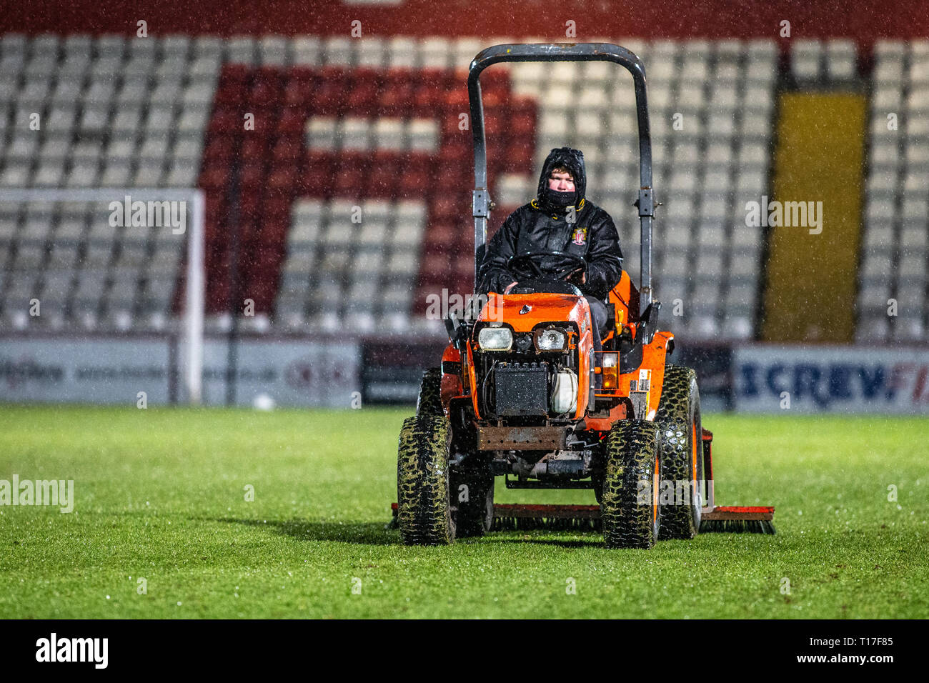 Groundsman entretien terrain de football dans la pluie Banque D'Images